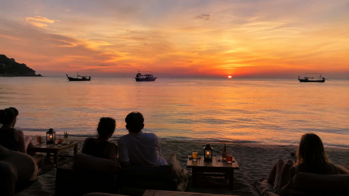 Coucher de soleil à Sairee Beach avec des voyageurs assis dans le sable