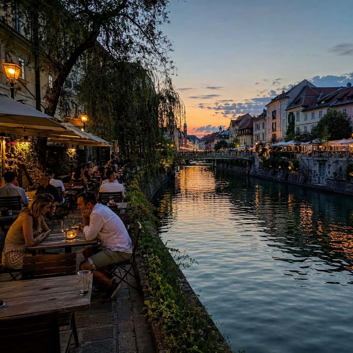 Les quais de la Ljubljanica en soirée, avec les terrasses allumées et les ponts du centre de Ljubljana