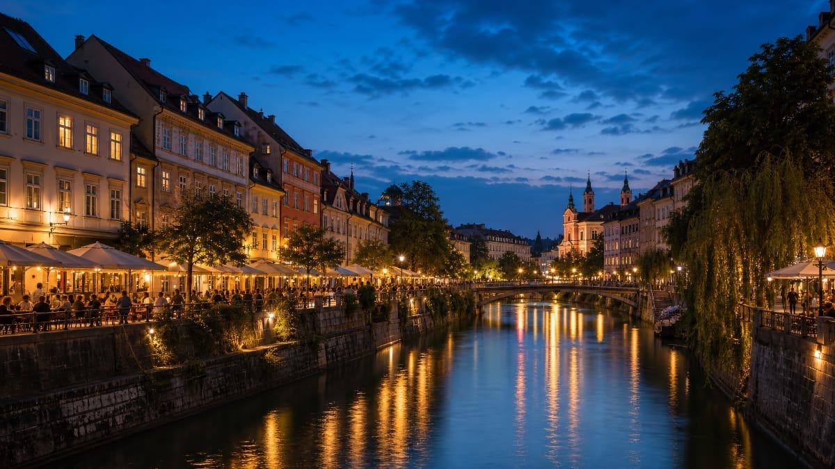 Terrasses animées au bord d’une rivière en ville à l’heure bleue, lumières reflétées dans l’eau.